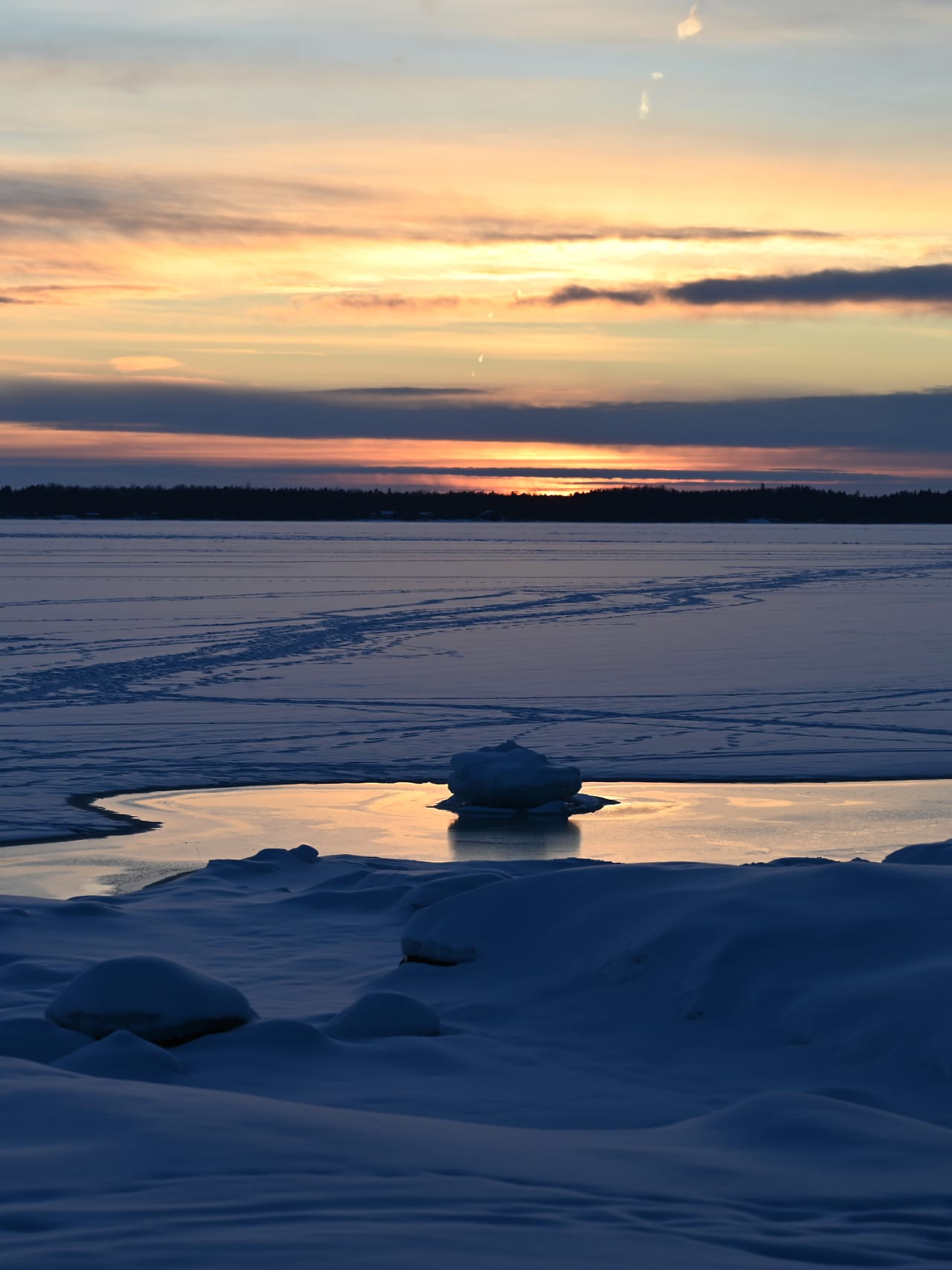 Jäätynyt avanto järvellä auringonlaskussa.
